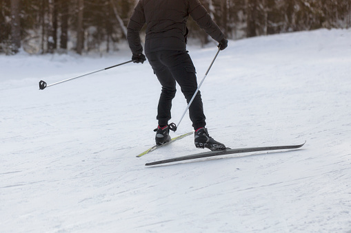 A man goes cross-country skiing in winter through the forest on a special track.