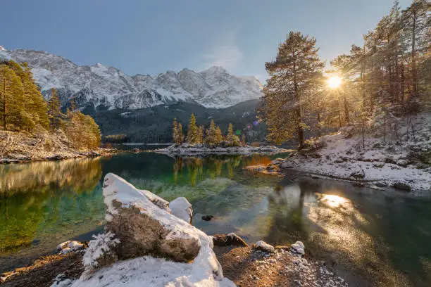 Snow-covered mountain forests and the Wetterstein range with Zugspitze in the afternoon sun reflected in the turquoise water of Lake Eibsee, Bavaria