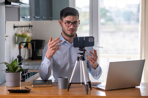 Businessman making video call on phone in kitchen