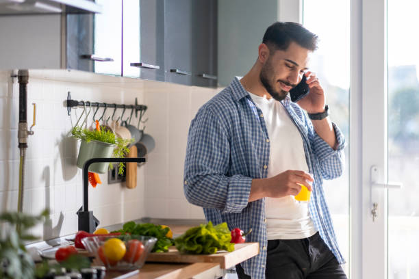 istock Young man standing in the kitchen and talking on the phone 1469793756