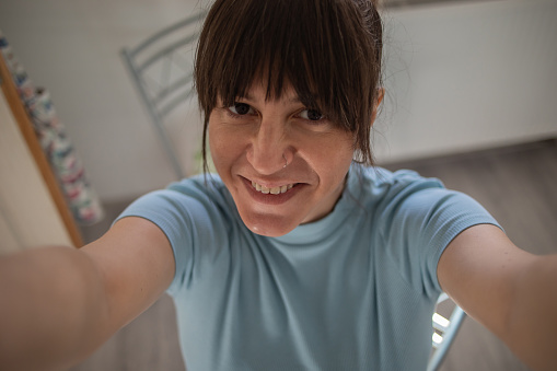 Young pretty smiling woman is making a selfie in her home.