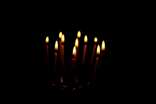 Birthday cake with lots of candles all in dark
