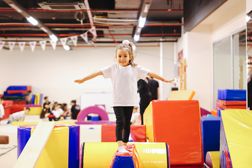Cute active child girl in sensory integration room, kindergarten. Kid is active leisure.Childhood and sporty lifestyle.Sports weekend in gymnastic center.Fitness,healthy, develop skills concept