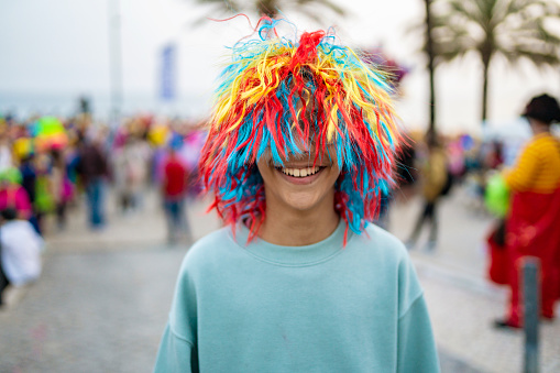 Child wearing colorful wig having fun at street carnival