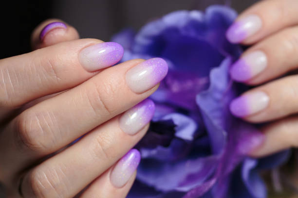 istock Female hands with violet nail design close-up. Artistic manicure with gradient violet glitter nail polish 1469802683