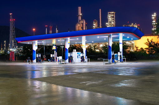 Gas station at night with oil refinery in the background