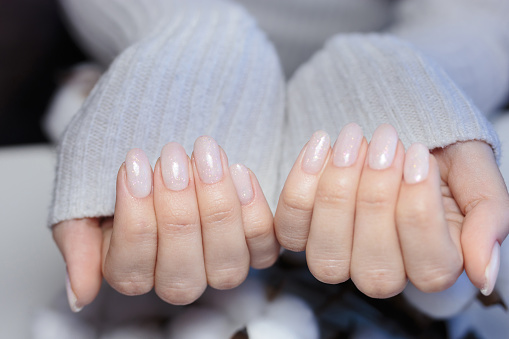 Women's hands with a beautiful pink manicure with glitter. Nail design. Manicure with gel polish close-up