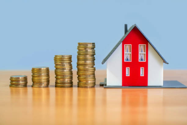 istock Ascending stacks of coins next to a model home 1469806489