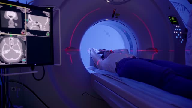 4k video CT scanning of abdomen of woman in medical clinic. Girl patient is doing CT computed tomography x-ray scan of chest for examination of abdomen in a CT scanning room.