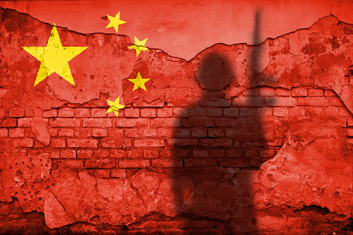 Flag of China painted on a concrete wall with soldier shadow