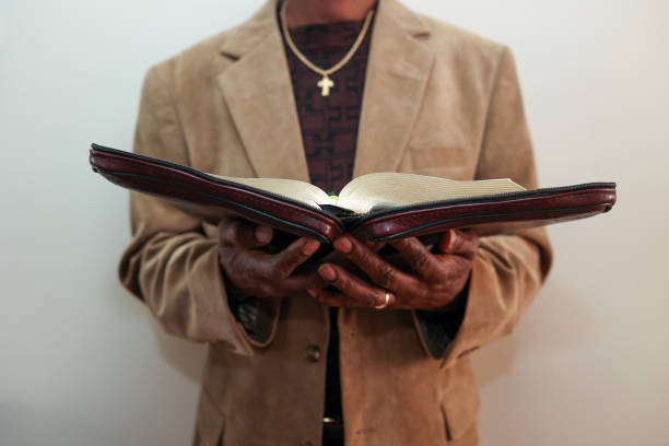 istock A black man holding an open Bible in his hand against a white background 1469809916