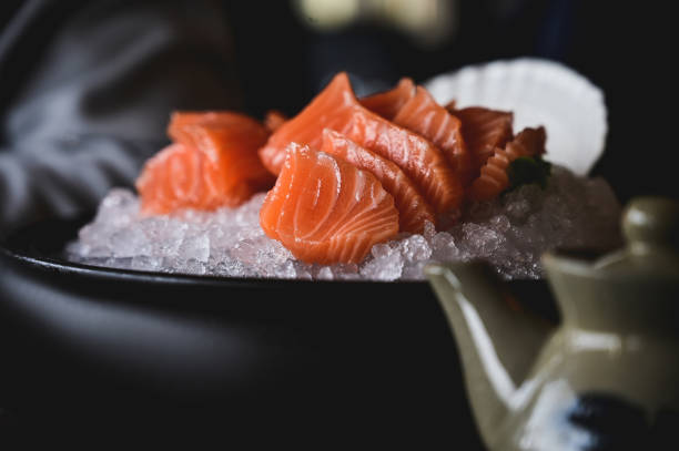 Slices of Raw salmon Sashimi in a black bowl in a sushi bar.