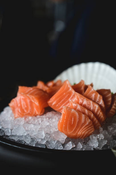 Fresh raw salmon on a black plate with ice in a restaurant.