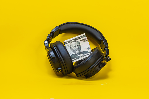 headphones money, for listening to music dollars, black color plastic, cash bills, stand on the surface of the yellow background. concept buy subscription plan to music.