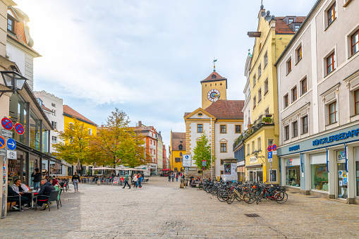 Colorful buildings with shops and cafes line the historic medieval streets and town squares in the Bavarian city of Regensburg, Germany, on the shores of Lake Danube at autumn.