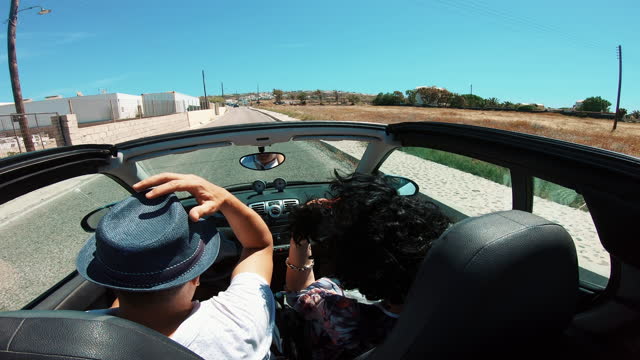 Couple traveling in a cabriolet convertible car, Santorini Island, Greece