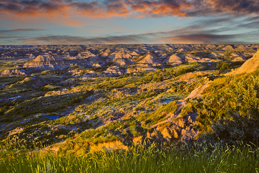 Theodore Roosevelt National Park lies where the Great Plains meet the rugged Badlands near Medora, North Dakota, USA.  The park's 3 units, linked by the Little Missouri River is a habitat for bison, elk and prairie dogs.  The park's namesake, President Teddy Roosevelt once lived in the Maltese Cross Cabin which is now part of the park.  This picture of the badlands at sunset was taken from the Painted Canyon Overlook.