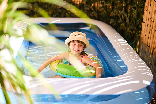 Little girl playing in inflatable pool. toddler girl floating in swimming pool on an inflatable tube