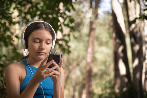 mujer con auriculares y smartphone escuchando musica en el parque
