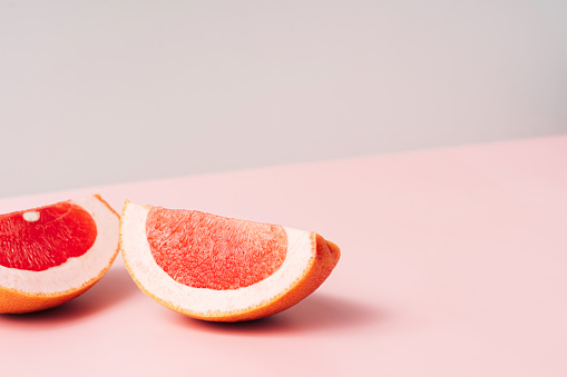 Two grapefruit slices against a green-pink background.