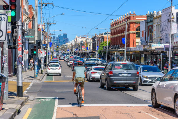 A very busy Sydney Road in Brunswick on a sunny day, with the Melbourne city skyline in the distance. stock photo
