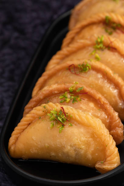 gujia también llamado gujiya, pirukiya, pirukia, pedakiya, karanji, basundi o gughra relleno de mawa, khoya, chasni, mava, khoa - bola de masa dulce india disfrutada en deepawali, teez, holi, diwali y teej - gujia fotografías e imágenes de stock