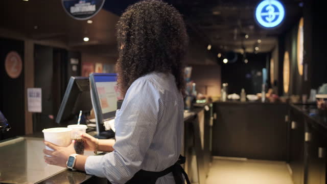 Movie theater waitress delivering popcorn and soda refills to customer