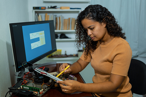 Woman studying while trying to repair computer motherboard.