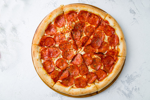 Sliced Pepperoni pizza on wooden board on concrete table top view