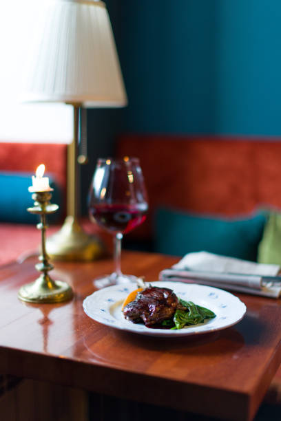 istock Duck leg confit on plate on wooden table with red wine glass vertical 1469855586
