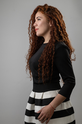 profile face of young latin woman smiling, female model with curly red hair, studio shot with natural beauty, skin texture