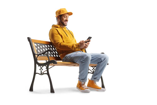 istock Cheerful guy sitting on a bench and using a smartphone 1469856154