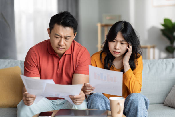 istock Confused asian couple checking bills, home interior 1469858784