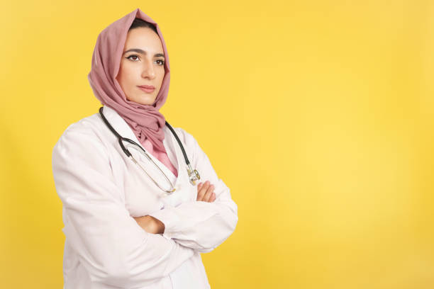 une femme médecin musulmane sérieuse avec les bras croisés détourne le regard - clothing professional occupation medical occupation doctor photos et images de collection