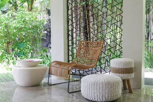 Half opened lounge area with all natural materials made furniture, rattan chairs with greenery behind