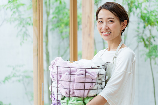 attractive asian woman holding laundry basket in a living room