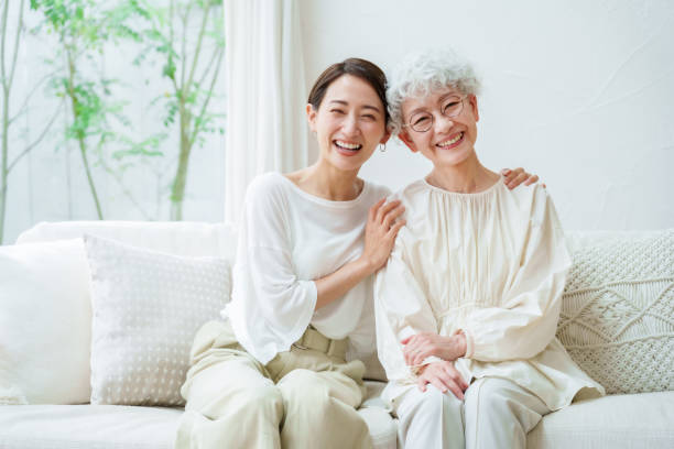 asian mother and daughter relaxing in a living room asian mother and daughter relaxing in a living room asian daughter stock pictures, royalty-free photos & images