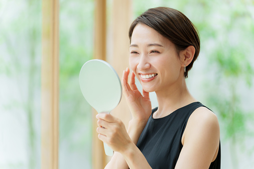 Atractiva mujer asiática con vestido negro mirando espejo photo