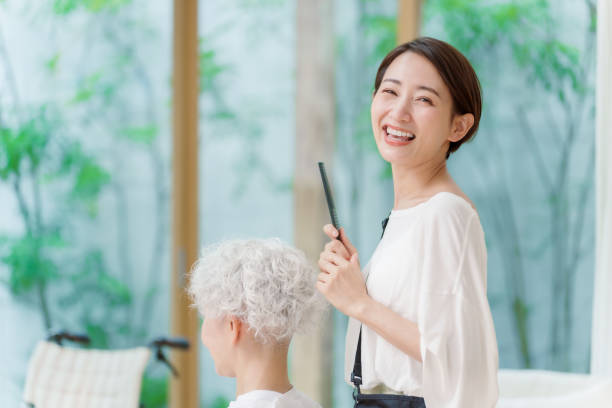 年配の女性の髪を切るアジアの若いスタイリスト - beautician ストックフォトと画像