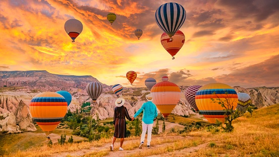 Cappadocia Turkey during sunrise, a couple mid age men and women on vacation in the hills of Goreme Cappadocia Turkey, men and woman looking sunrise with hot air balloons in Cappadocia Turkey