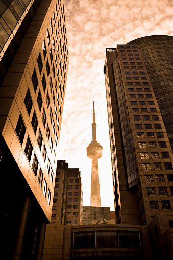 October 30, 2022 - Toronto, Ontario, Canada: View of CN Tower through highrise buldings in downtown Toronto at sunset golden hour