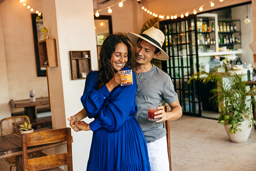 Young man and woman drinking cocktails, laughing and dancing - stock photo