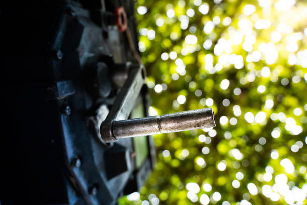 A crooked starter is inserted into the engine of a walk-behind tractor close-up on a blurred bright green background. Device for manual start of the tractor engine. Agricultural activity