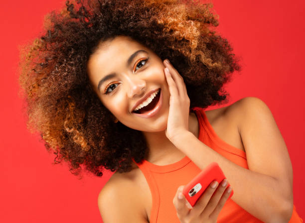 lovely ethnic woman holds modern mobile phone, uses electronic device on surfing web, connected to wireless internet stock photo