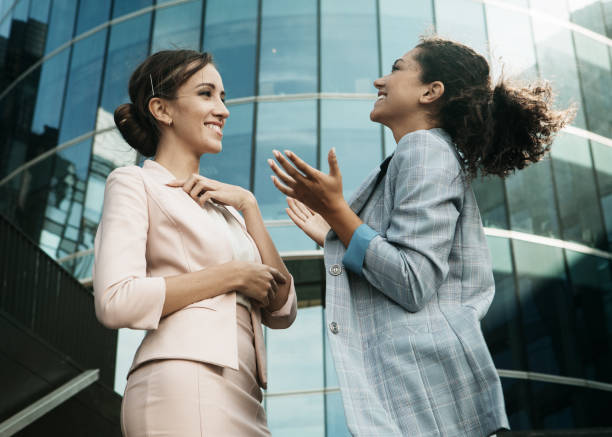 Two business women having a casual meeting or discussion near a modern office stock photo