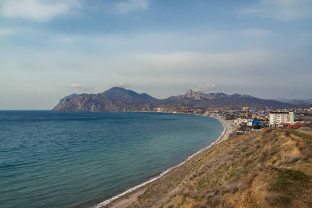 View of seaside resort city Koktebel , mountain Kara Dag from hill in spring. Crimea View of seaside resort city Koktebel , mountain Kara Dag from hills in spring. Crimea feodosiya stock pictures, royalty-free photos & images