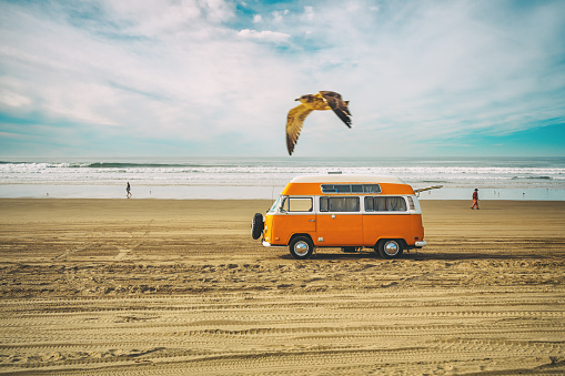 Oceano, California, USA - January 12, 2022. Vintage yellow van on the beach with cloudy sky on background, retro color effect. Oceano Dunes, California Central Coast