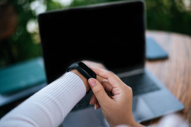 istock Young woman using smartwatch and workon laptop computer in cafe 1469896646
