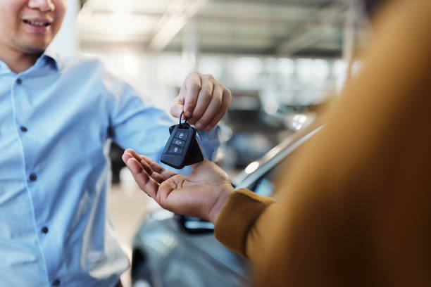 Here are your new car keys! Close up of unrecognizable salesman giving car keys to his black customer in a showroom. car key stock pictures, royalty-free photos & images