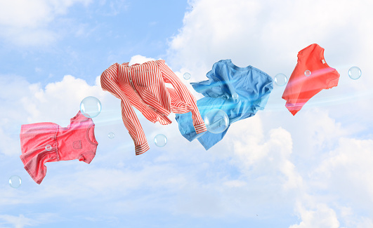 Washing powder bubbles and clothes flying in blue cloudy sky